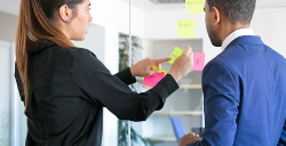 professional-young-colleagues-working-with-stickers-focused-female-worker-sticking-note-glass-focused-businessman-blue-suit-standing-near-her-teamwork-business-collaboration-concept 1